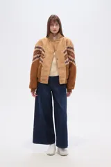 Chaqueta holgada de poliéster en color tostado con forro de corderito, cuello de solapa y cierre frontal con botones. Presenta mangas con apliques de diseño geométrico en tonos marrones y azules.