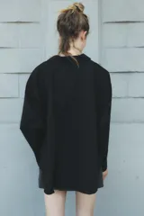 Camisa negra de cuello solapa y manga larga amplia. Tiene un bolsillo de parche en el delantero, detalle de pliegues y cierre frontal con botones.