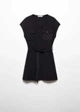 Vestido corto negro de tejido fluido, con cuello redondo y mangas cortas. Presenta trabillas, diseño evasé, dos bolsillos de solapa con botón en el pecho, lazo ajustable y cierre delantero con botones.