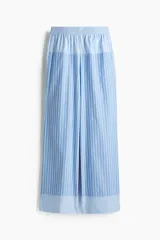 Pantalón de corte holgado en tejido fresco de algodón a rayas verticales celestes y blancas. Modelo de tiro alto con elástico fruncido en la cintura, bolsillos laterales discretos y piernas rectas.