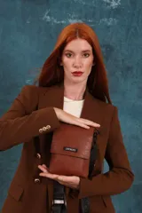 Bandolera tipo phone bag pequeña, color marrón claro, con correa de galón regulable. Tiene un compartimento principal y un bolsillo adicional con tapa.