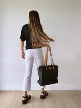Bolso tipo tote bag de cuero negro con forro de tela, doble asa de cuero color suela, bolsillo frontal y bolsillo interno.