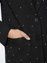 Blazer negro de corte oversize con solapas de muesca, cierre con dos botones y bolsillos delanteros con solapa. Decorado con pequeños cristales plateados.