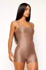 Jumpsuit corto color marrón, de calce ajustado, con escote cuadrado y espalda descubierta. Confeccionado en tejido elástico acanalado con efecto brillante.