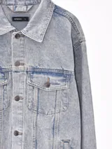 Campera de jean negra con botones metálicos, bolsillos frontales con solapa y cuello clásico.