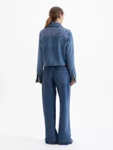 Jeans de denim azul, tiro medio y corte recto, con bordado integral en patrón de rombos en hilo rosa y pequeños bordados de labios en color bordeaux.