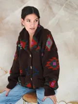 Saco de lana marrón con diseño geométrico multicolor, cuello con solapa, cierre frontal con botones y bolsillos delanteros.