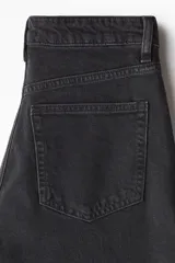 Pantalón de jean negro de corte ancho, tiro alto y largo tobillero.