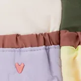 Mochila pequeña con diseño de bloques de color en tonos beige, verde oliva, lila y amarillo. Cuenta con un bolsillo frontal acolchado con estampado de pequeños corazones, cierre de cremallera y asa superior en color rosado.