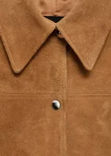 Chaqueta corta de cuero gamuzado color marrón claro, con cuello camisero, cierre frontal con botones a presión y bolsillos de parche en el frente.