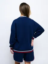 Buzo de felpa azul marino con mangas raglán rojas y detalles tricolor en puños, mangas y cuello. Incluye logo de Umbro bordado en el pecho y escudo del Club Nacional de Football.