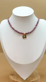 Collar de cinco hilos de cuentas facetadas de jade de Malasia color borgoña, con cuentas doradas y dijes colgantes dorados con incrustaciones de strass: estrella, espiral, mano de Fátima, luna creciente y esqueleto de pez.