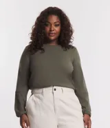 Blusa verde militar en suedine texturizada, con cuello redondo, manga larga con recortes y tiradores en los puños.