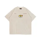 Remera color crema de corte recto con cuello redondo y mangas cortas. Estampado frontal con logo de la marca y texto.