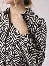 Camisa de manga larga con estampado de cebra en tonos beige, marrón y lila. Tiene cuello clásico, cierre con botones y un bolsillo en el pecho.