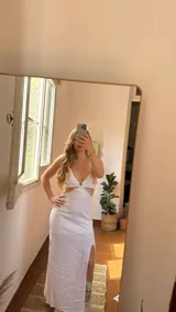 Vestido largo blanco de lino con abertura lateral en la falda. El corpiño es tipo bralette con escote en V y tirantes anchos que se cruzan en la espalda.