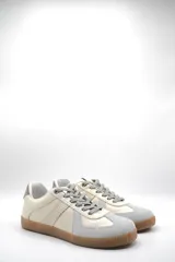 Zapatillas urbanas de cuero color crema con puntera y talón en gamuza gris, suela de goma marrón y cordones grises.