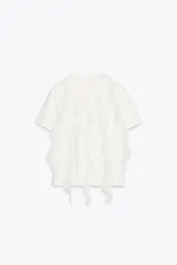 Camiseta blanca de algodón con cuello redondo, manga corta y volantes de gasa en el frente.