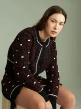 Cardigan de punto negro con diseño de rombos en color borgoña y lunares blancos. Tiene cuello redondo, cierre frontal con botones negros y ribete acanalado en cuello, puños y bajo.