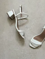 Sandalias doradas de fiesta con tiras finas y taco cuadrado bajo.