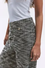 Pantalón ancho de tiro alto con elástico oculto en la cintura, confeccionado en tejido texturizado a cuadros en tonos grises. Presenta pliegues delanteros y traseros, bolsillos delanteros decorativos con botón metálico.