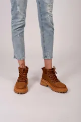 Borcegos marrones de cuero con textura símil cocodrilo, caña media con detalle de gamuza en la parte superior, cordones marrones y suela track.