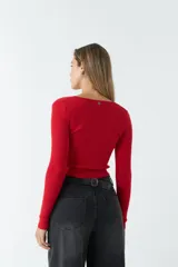 Top rojo de tejido de punto acanalado, con escote en V y mangas largas. Presenta un fruncido ajustable en el centro del frente.