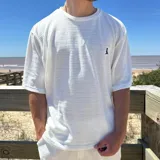 Remera blanca de tejido texturizado con cuello redondo y manga corta.