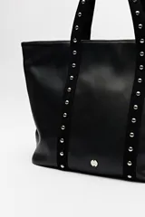 Bolso shopper de símil cuero color beige, con asas largas decoradas con tachas metálicas.