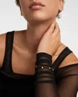 Pulsera dorada con cadena fina y cuatro dijes colgantes de circonitas multicolores en forma de gota.