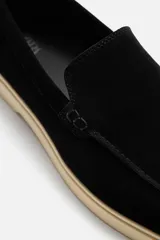 Mocasín casual de hombre color negro, con capellada de cuero serraje, corte liso con detalle de bordón y suela color crema.