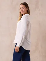 Camisa blanca de manga larga con cuello con solapa y abertura central con botones. Tiene dos bolsillos delanteros aplicados.