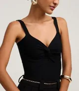 Top cropped blanco de tirantes anchos, confeccionado en tejido de punto texturizado, con escote en V y detalle de nudo o torcido en el centro del busto.