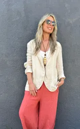 Blazer de lino color beige, con cuello de solapa, cierre de un botón, bolsillos frontales y mangas largas con puños arremangados.