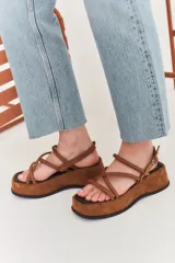 Sandalias marrones de plataforma con tiras finas cruzadas y hebilla ajustable en el tobillo.
