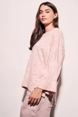 Sweater rosa con mangas acampanadas y cuello redondo. Tejido suave y confortable de algodón, acrílico y lino.