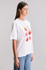 Remera blanca de algodón con cuello redondo y mangas cortas. Estampado frontal con diseño de frambuesas y texto 'Berry Into You'.