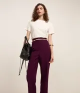 Pantalón de vestir azul marino, de corte zanahoria, con cinturón fino negro con hebilla dorada.