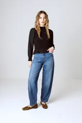 Blusa negra con cuello alto fruncido, mangas largas abullonadas y detalle de volado en el ruedo.