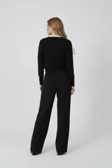 Cardigan negro de acrílico, ajustado al cuerpo, con cuello a la base, manga larga y cierre frontal con botones.