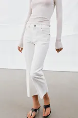 Jeans de tiro medio con corte flare y largo cropped. Presentan diseño de cinco bolsillos, trabillas en la cintura, raya planchada en el delantero y bajo desflecado. Cierre frontal con cremallera y botón.