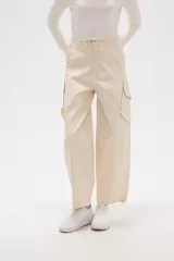 Pantalón cargo de jean color beige, de calce bajo, con bolsillos laterales y ajuste con cordón en la cintura.