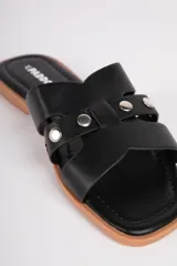 Sandalias bajas de símil cuero con punta cuadrada, cintas caladas y tachas sobre el empeine.
