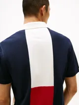 Chomba Tommy Hilfiger de hombre con diseño color block en blanco y azul marino. Tiene cuello tipo chomba, cartera de dos botones y logo bordado en el pecho.