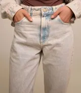 Pantalón de jean celeste, modelo mom, con lavado dirty, cintura con trabillas, cierre por botón y cremallera y bolsillos.