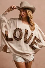 Remerón color crema con mangas largas abullonadas y aplique de letras con estampado animal print formando la palabra "LOVE".