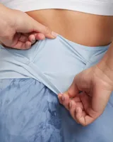 Short de running Nike Trail, color celeste con estampado abstracto en azul y gris. Cuenta con tecnología repelente al agua, cintura elástica con cordón ajustable, tres bolsillos internos y un bolsillo con cierre en el muslo derecho.