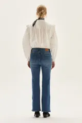 Jean de tiro medio, color azul medio, con silueta ligeramente acampanada desde la rodilla.