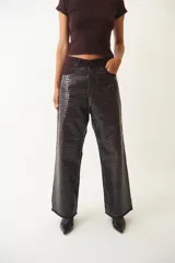 Pantalón de jean de corte ancho con estampado de piel de cocodrilo color bordó.