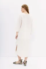 Vestido midi tipo túnica color blanco, de lino y algodón. Tiene calce recto, escote redondo con botones y bordados en hilo en el frente, sisas y ruedo.